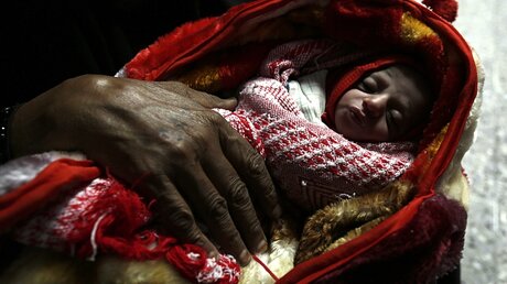 Kind in einer Tragetasche / © Yahya Arhab (dpa)