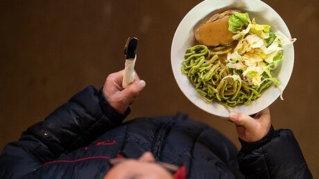 Mann mit einem Teller Essen in einer Vesperkirche  / © Sebastian Gollnow (dpa)