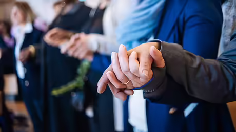 Menschen halten sich an den H&auml;nden und beten das Vaterunser / &copy; Jan Schmidt-Whitley (KNA)