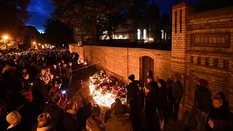 Menschen legen an der Mauer der Synagoge Blumen und Kerzen nieder / © Hendrik Schmidt (dpa)