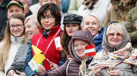 Menschen winken mit Landesfahnen von Lettland und dem Vatikan in Riga / © Paul Haring (KNA)