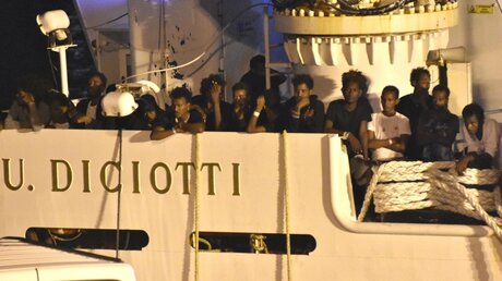 Migranten stehen an Bord des Schiffs "Diciotti" und warten darauf von Bord zu gehen / © Orietta Scardino (dpa)