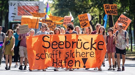 Mit Plakaten und einem Banner demonstrieren Menschen für die Seenotrettung / © Marius Becker (dpa)