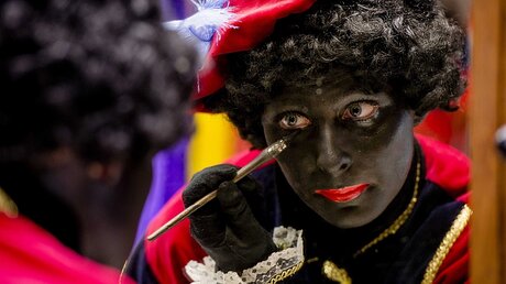 Niederlande, Soest: Eine Frau schminkt sich als Zwarte Piet / © Robin Van Lonkhuijsen (dpa)