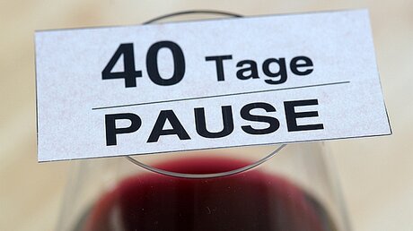 Ein Glas Rotwein mit der Aufschrift "40 Tage Pause" / © Matthias Greve (KNA)