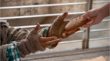 Obdachloser bekommt ein Stück Brot / © N.Pipat (shutterstock)