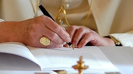 Benedikt XVI. unterschreibt ein Dokument. / © N.N. (KNA)