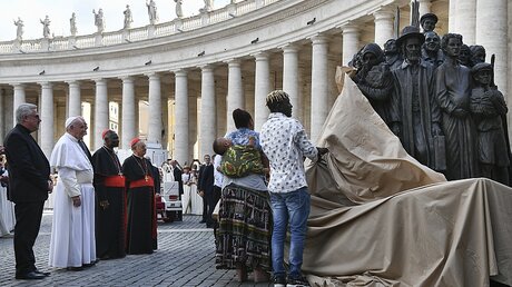 Papst Franziskus steht während der Enthüllung einer Flüchtlingsskulptur auf dem Petersplatz  / © Vincenzo Pinto (dpa)