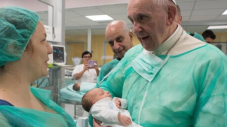 Papst Franziskus hält ein Baby auf dem Arm / ©  L'osservatore Romano Press Office (dpa)