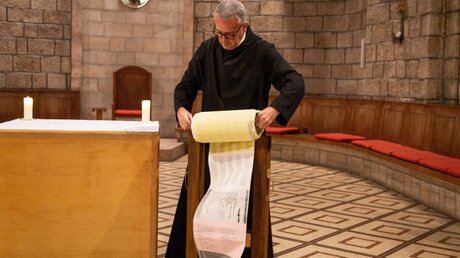 Pater Matthias mit einer meterlangen Schriftrolle mit Namen aus aller Welt / © Andrea Krogmann (KNA)