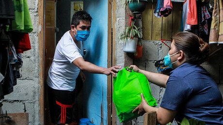 Philippinen: Ein Anwohner eines Slums erhält eine Tasche mit Hilfsmitteln / © Rouelle Umali (dpa)