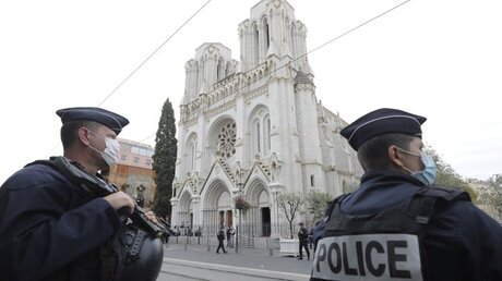 Polizeibeamte stehen in der Nähe des Tatorts einer Messerattacke vor der Kirche Notre-Dame in der südfranzösischen Küstenstadt Nizza. / © Eric Gaillard (dpa)