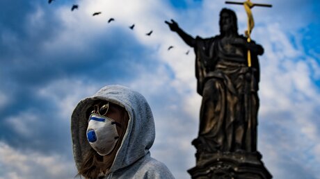 Prag: Eine Frau mit Mundschutz steht auf der Karlsbrücke / © Roman Vondrou (dpa)