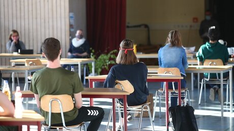 Schüler mit Mundschutz sitzen bei der Prüfungsvorbereitung in einer Turnhalle / © Bodo Schackow (dpa)