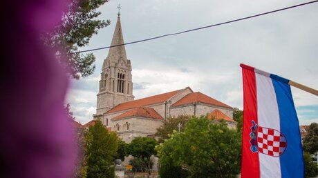 Symbolbild: Kroatische Flagge vor einer Kirche / © Antonio Batinic (shutterstock)