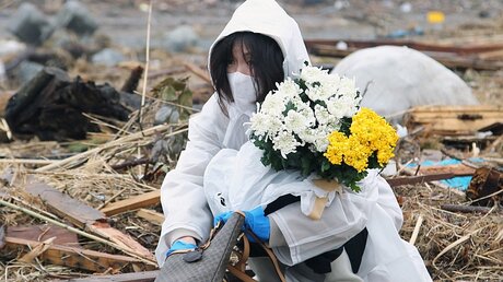 Trauer in Fukushima: Eine Frau betet und legt Blumen am Unglücksort nieder   / © Koichi Kamoshida (dpa)