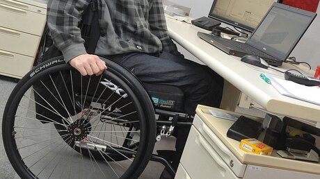 Ein Mann in einem Rollstuhl an seinem Arbeitsplatz / © Stefan Puchner (dpa)