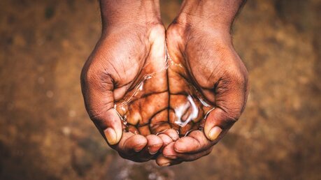 Ein Mann hält Wasser in seinen Händen / © avijit bouri (shutterstock)