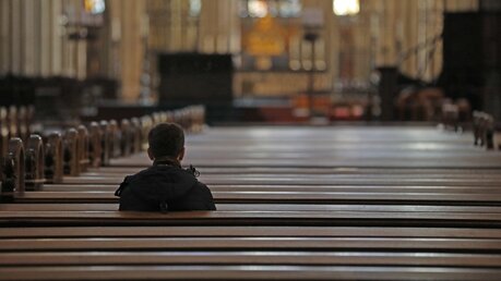Ein Mann sitzt zum Gebet alleine im Kölner Dom / © Oliver Berg (dpa)