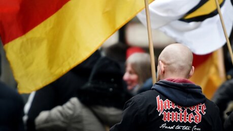 Ein rechtsextremer Demonstrant steht zwischen Deutschlandfahnen / © Caroline Seidel (dpa)