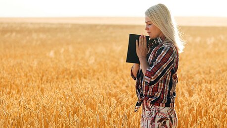 Eine Frau mit einer Bibel in der Hand auf einem Feld / © Andrew Angelov (DR)