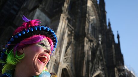 Eine Karnevalistin lacht vor dem Dom / © Oliver Berg (dpa)