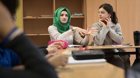Eine Muslima im Gespräch mit ihren Mitschülern / © Jörg Carstensen (dpa)