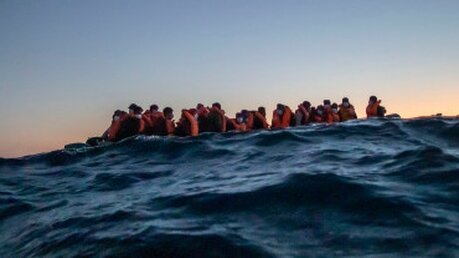 Geflüchtete treiben in einem Boot auf dem Mittelmeer / © Bruno Thevenin (dpa)
