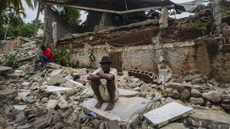 Haiti: Ein Mann hockt auf Trümmern / © Fernando Llano (dpa)