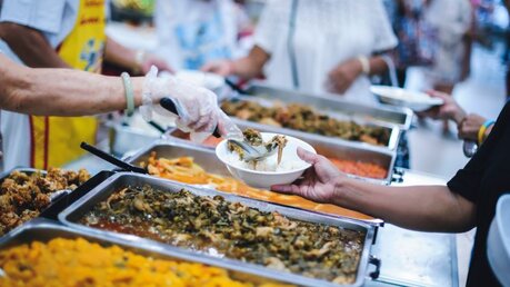 Helfer teilen Essen an Bedürftige aus / © addkm (shutterstock)