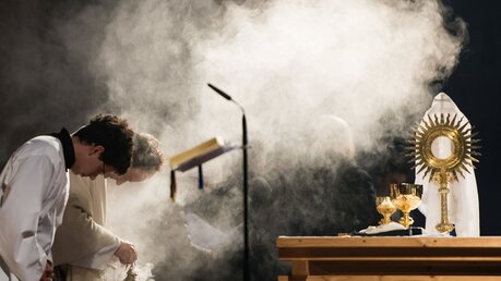 Ein Pfarrer hält ein Weihrauchfass und verbeugt sich zusammen mit einem Messdiener vor dem Altar / © Sebastian Widmann (KNA)