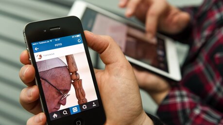 Fotos von Papst Franziskus sind auf einem Smartphone und einem Tablet zu sehen / © Harald Oppitz (KNA)
