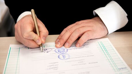 Ein Pfarrer unterschreibt ein Dokument / © Maria Irl (KNA)