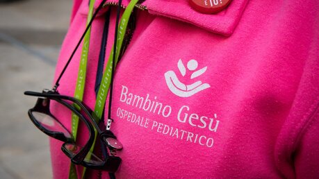 Eine Frau trägt einen pinkfarbenen Pullover des vatikanischen Kinderkrankenhauses Bambino Gesu in Rom / © Cristian Gennari/Romano Siciliani (KNA)
