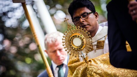 Ein Priester trägt eine goldene Monstranz bei einer Fronleichnamsprozession / © Lars Berg (KNA)