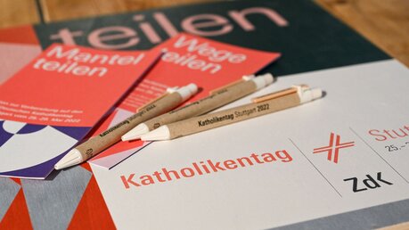 Flyer und Kugelschreiber liegen auf einem Logo des 102. Deutschen Katholikentags / © Harald Oppitz (KNA)