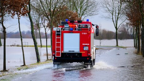 Ein Fahrzeug der Feuerwehr fährt am 29.12.2023 auf einer teilweise überfluteten Straße unweit der Aller. Die Hochwasserlage bleibt in vielen Regionen Niedersachsens angespannt / © Philipp Schulze/dpa +++ dpa-Bildfunk +++ (dpa)