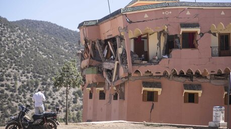 Erdbeben in Marokko: Ein Mann steht neben einem beschädigten Hotel nach dem Erdbeben im Dorf Moulay Brahim / © Mosa'ab Elshamy/AP (dpa)