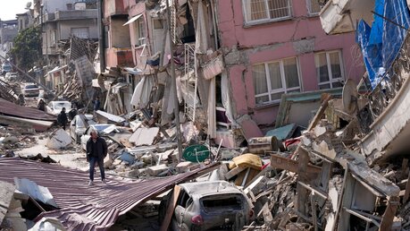 Türkei, Hatay: Ein Mann geht über die Trümmer eingestürzter Gebäude / © Hussein Malla (dpa)