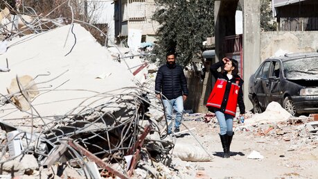 Türkei, Islahiye: Eine Angehörige eines türkischen Rettungsdienstes und ein Mann gehen entlang von Trümmer, die durch das Erbeben ausgelöst wurde / © Zakariya Yahya (dpa)