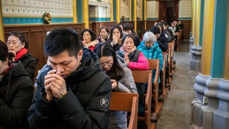 Gottesdienstbesucher knien zum Gebet in den Kirchenbänken während einer Messe / © Gilles Sabrie (KNA)