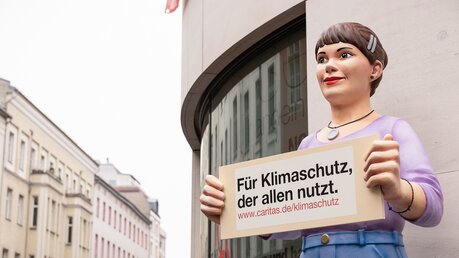 Aufstellpuppe "Jenny" von der Caritas hält ein Schild mit der Aufschrift "Für Klimaschutz, der allen nutzt" bei der Demonstration "Globaler Klimastreik" am 3. März 2023 in Berlin. / © Thomas Koy (KNA)
