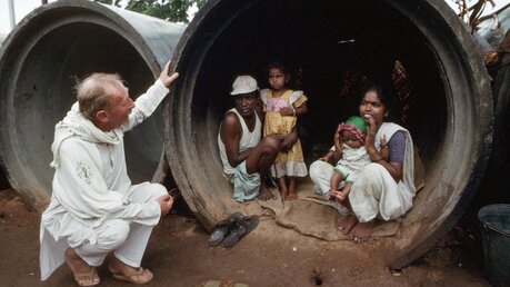 Ein Missionar bei einer Familie, die in einem Stück Rohr lebt (KNA)