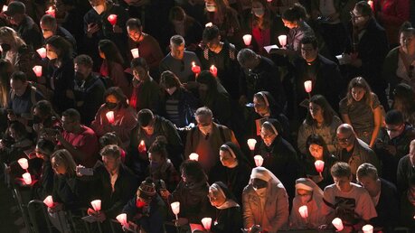 Menschen halten Kerzen und nehmen am Kreuzweg teil, den Papst Franziskus am Karfreitagabend vor dem Kolosseum leitet. / © Alessandra Tarantino/AP (dpa)