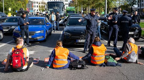 Klimaaktivisten haben sich in der Münchner Innenstadt auf die Fahrbahn geklebt und blockieren die Straße / © Lennart Preiss (dpa)