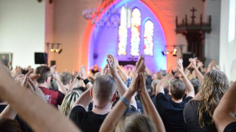 Gottesdienstbesucher mit erhobenen Händen bei einem Konzert in der evangelischen Heiligen-Geist-Kirche / © Michael Althaus (KNA)