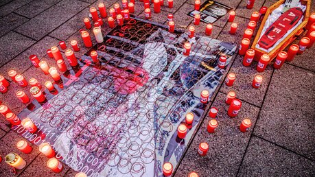 Ein Plakat, brennende Opferlichter und ein symbolischer Sarg bei einer Kundgebung von Betroffenen sexuellen Missbrauchs in der katholischen Kirche am 21. Januar 2022 vor dem Essener Dom. / © Andre Zelck (KNA)
