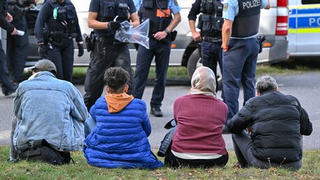 Unerlaubt eingereiste Migranten werden am 11.10.2023 von Beamten der Bundespolizei bei einem Aufgriff nahe der deutsch-polnischen Grenze im brandenburgischen Forst in der Lausitz bewacht. / © Patrick Pleul (dpa)