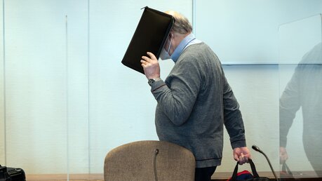 Köln: Der angeklagte katholische Priester U. hält sich im Gerichtssaal eine Mappe vor das Gesicht / © Federico Gambarini (dpa)