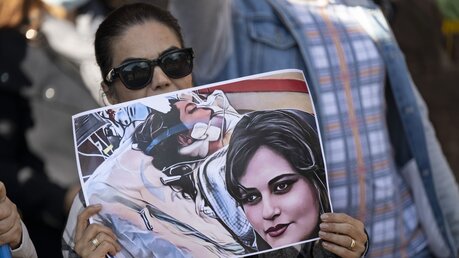 Eine Demonstrantin hält ein Plakat mit dem Bild der gestorbenen 22-jährigen Mahsa Amini in den Händen / © Boris Roessler (dpa)